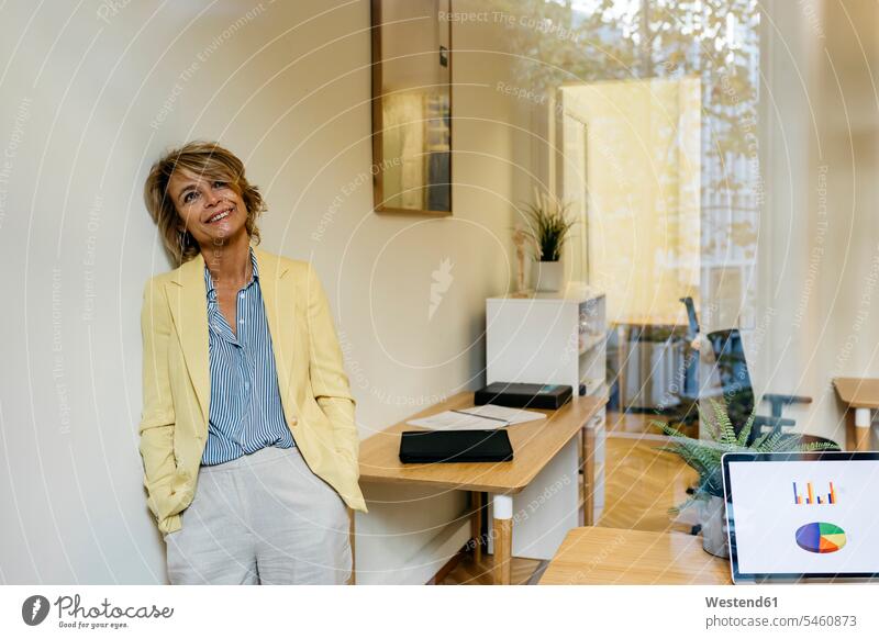 Contemplating female entrepreneur leaning on wall seen through window in office color image colour image outdoors location shots outdoor shot outdoor shots day