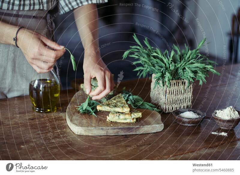 Young woman garnishing homemade chickpea and herb cake Chickpea Chick Peas Cicer arietinum Chickpeas arranging preparing Food Preparation preparing food