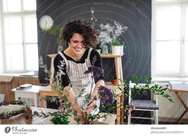 Smiling young woman arranging flowers in a small shop Occupation Work job jobs profession professional occupation human human being human beings humans person