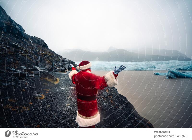Iceland, back view of Santa Claus standing in front of glacier glaciers Father Christmas ice icy X-Mas yule Xmas X mas celebration Red-Letter Day Festive Day