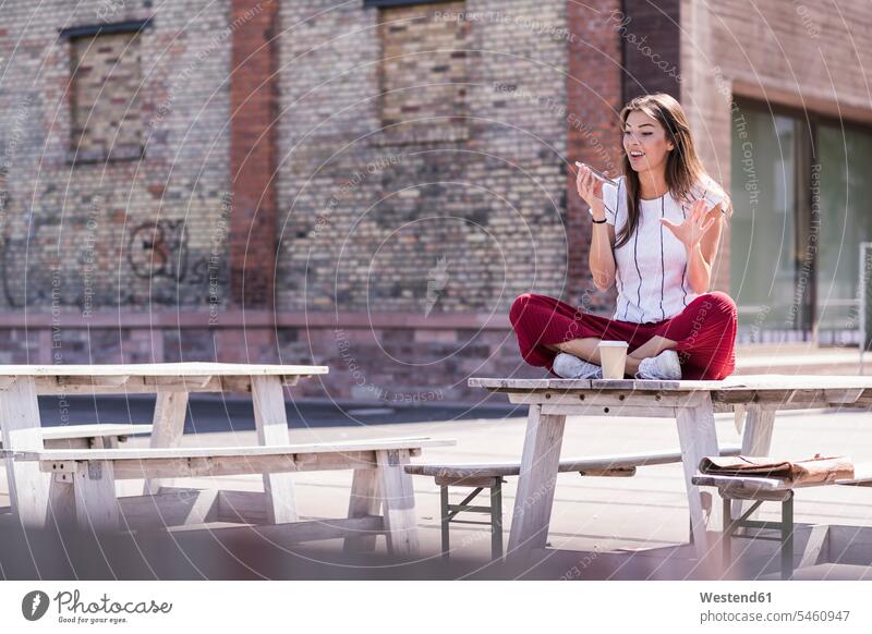 Young woman sitting on table in a beer garden using cell phone human human being human beings humans person persons caucasian appearance caucasian ethnicity