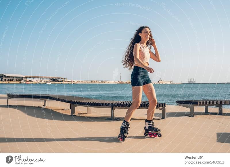 Young woman inline skating on promenade at the coast delight enjoyment Pleasant pleasure happy content Contented Emotion pleased free time leisure time
