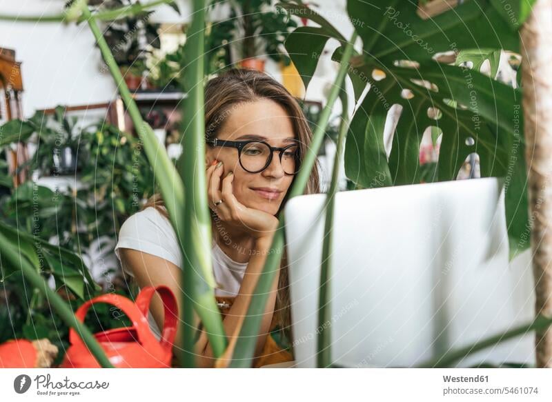 Young woman using laptop surrounded by plants Occupation Work job jobs profession professional occupation computers Laptop Computer Laptop Computers laptops