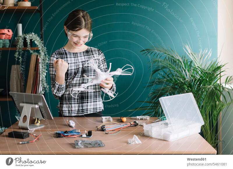 Smiling girl holding drone gesturing while standing against wall at home color image colour image indoors indoor shot indoor shots interior interior view