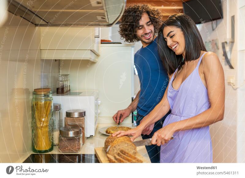 Smiling young couple preparing meal in kitchen at home color image colour image Spain friendship bonding community leisure activity leisure activities free time
