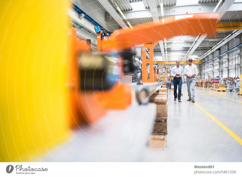 Two men walking and talking on factory shop floor human human being human beings humans person persons caucasian appearance caucasian ethnicity european 2