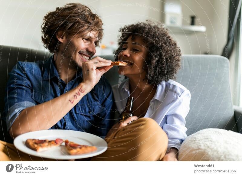 Happy couple sitting on couch eating pizza Pizza Pizzas happiness happy twosomes partnership couples Seated settee sofa sofas couches settees Food foods