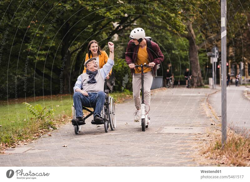 Senior man in wheelchair having fun with his adult grandchildren outdoors human human being human beings humans person persons caucasian appearance