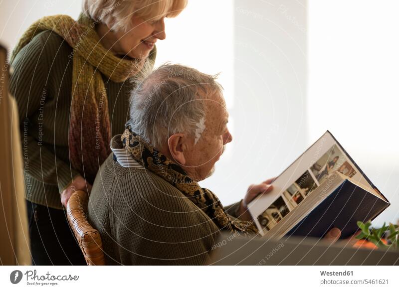 Senior couple looking at photo album surrounded by cardboard boxes in an empty room human human being human beings humans person persons caucasian appearance