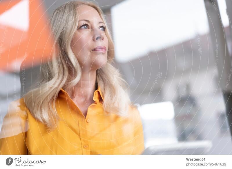 Close-up of thoughtful businesswoman looking away in home office seen through window color image colour image Germany indoors indoor shot indoor shots interior