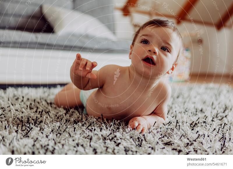 Happy baby playing on carpet lying laying down lie lying down infants nurselings babies crawling people persons human being humans human beings brown hair