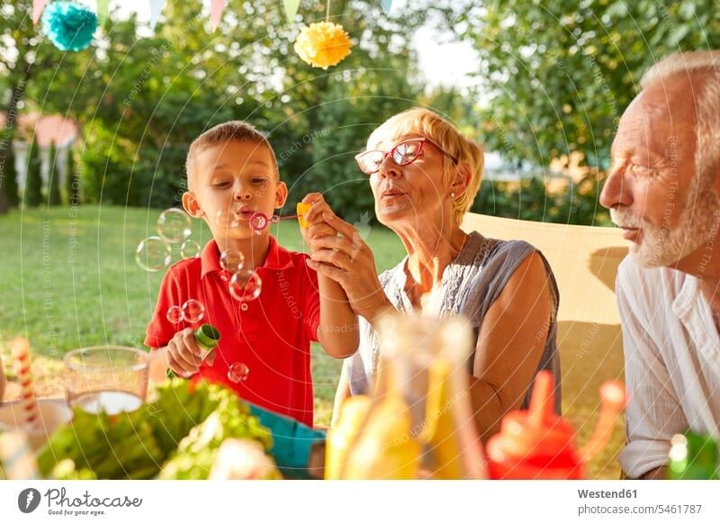 Grandmother and grandson blowing soap bubbles on a garden party Garden Party Garden Parties grandmother grandmas grandmothers granny grannies grandsons