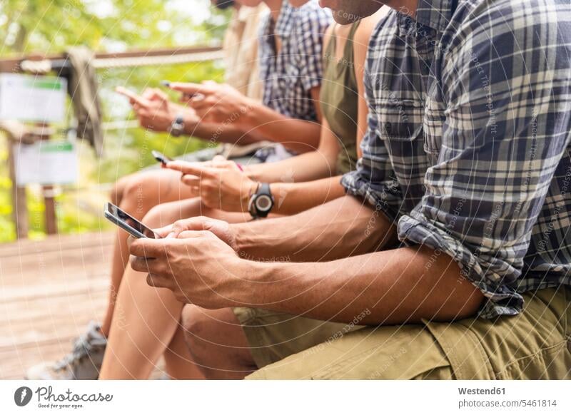 Italy, Massa, hikers in the Alpi Apuane mountains looking at their smartphones and sitting on a bench friends mate eyeing benches mobile phone mobiles