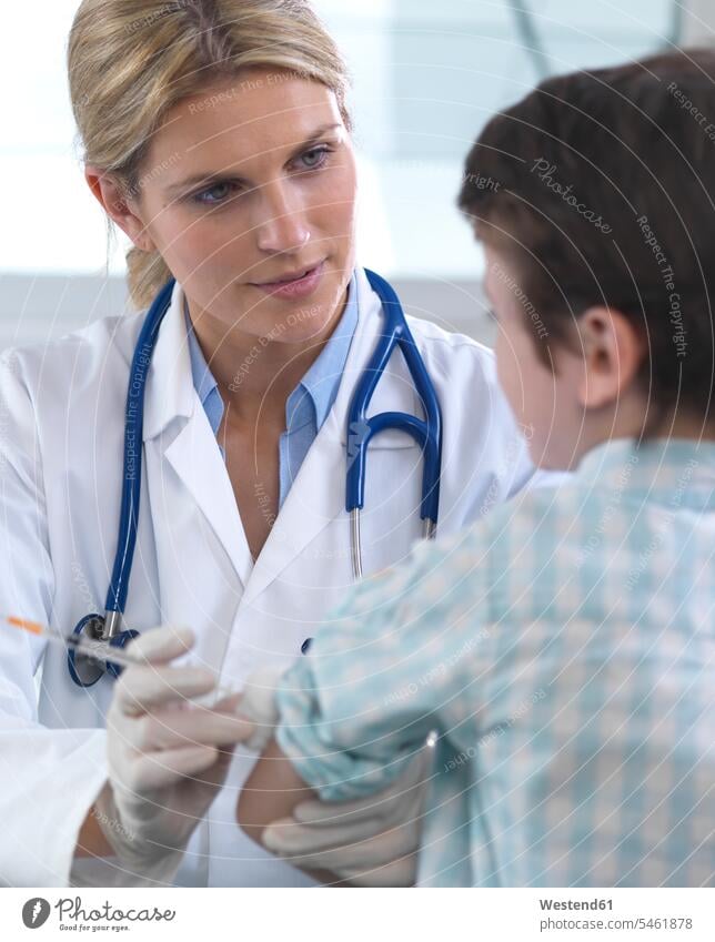 Female doctor giving a young boy a vaccination in the clinic human human being human beings humans person persons caucasian appearance caucasian ethnicity