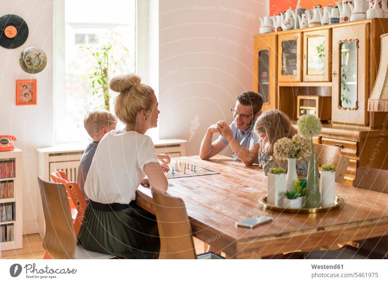 Happy family playing board game on dining table at home color image colour image Germany indoors indoor shot indoor shots interior interior view Interiors day