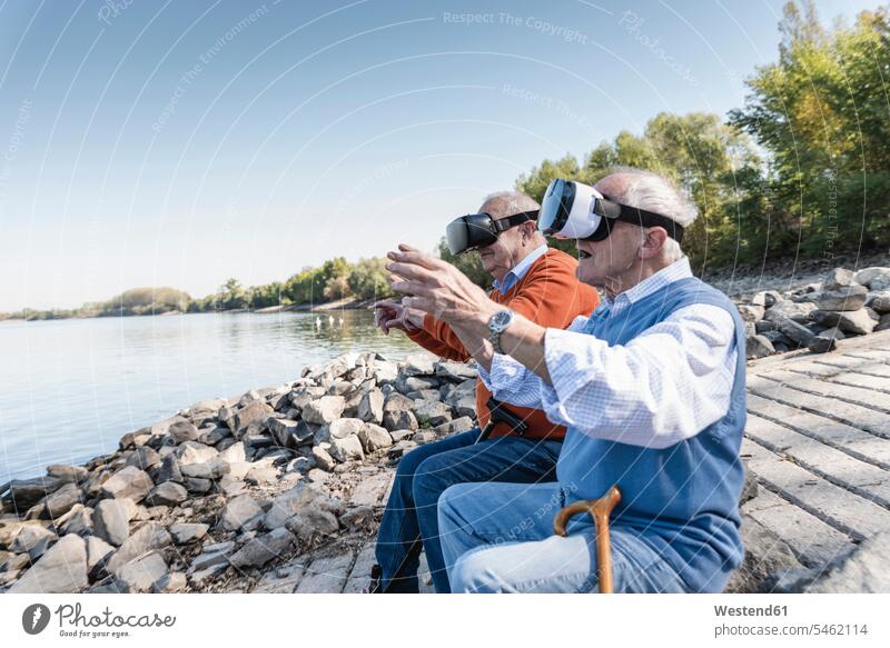 Two old friends sitting by the riverside, using VR glasses playing game games riverbank Virtual Reality Glasses Virtual-Reality Glasses virtual reality headset
