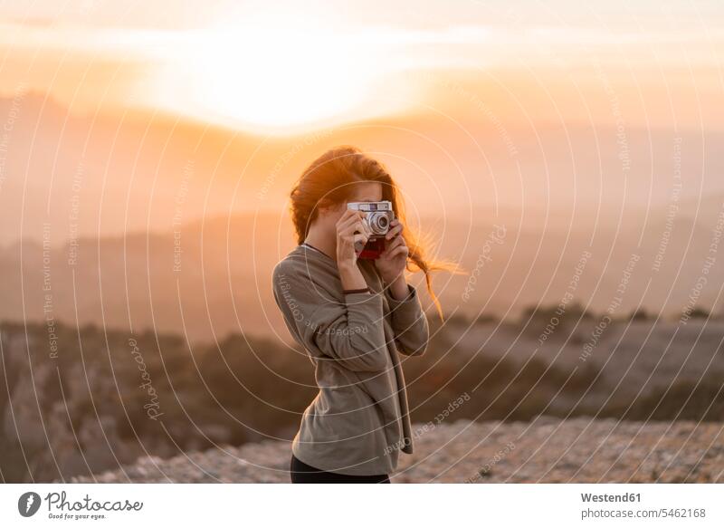 Spain, Barcelona, Natural Park of Sant Llorenc, woman taking a picture with vintage camera at sunset females women cameras photographing sunsets sundown Adults