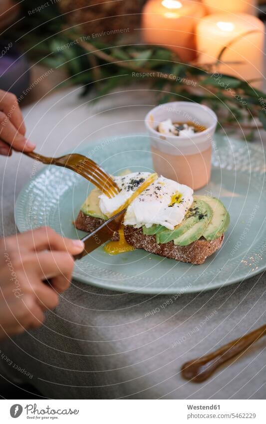 Close-up of woman cutting bread with avocado on garden table with candles Bread Breads Avocado Avocados Persea americana females women Food foods food and drink