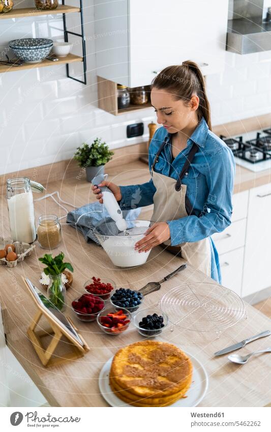 Young woman preparing a cream cake, using tablet Food Preparation preparing food digitizer Tablet Computer Tablet PC Tablet Computers iPad Digital Tablet