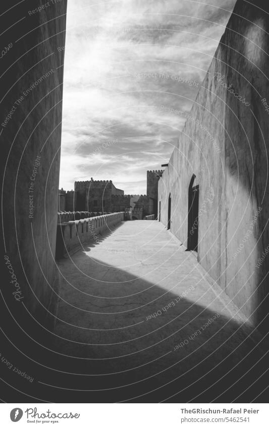 Black and white image of a castle with clear starry shadows Oman Castle Stone Old Shadow Light Historic Architecture Building Wall (building) Wall (barrier) Sky