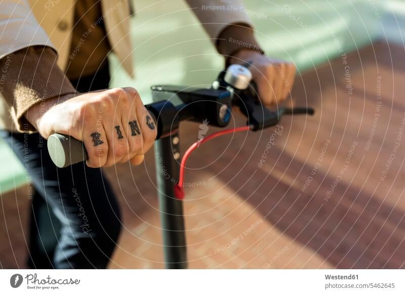 Hand of tattooed man holding handlebar of E-Scooter, close-up men males human hand hands human hands electric electrical electric scooter tattoos Adults