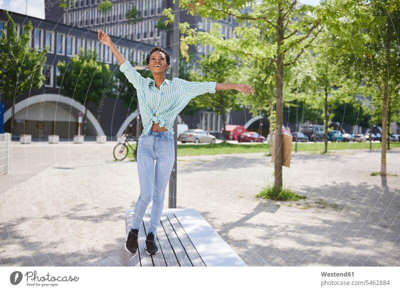 Happy young woman balancing on bench balance benches females women happiness happy Balance Equilibrium balanced Adults grown-ups grownups adult people persons