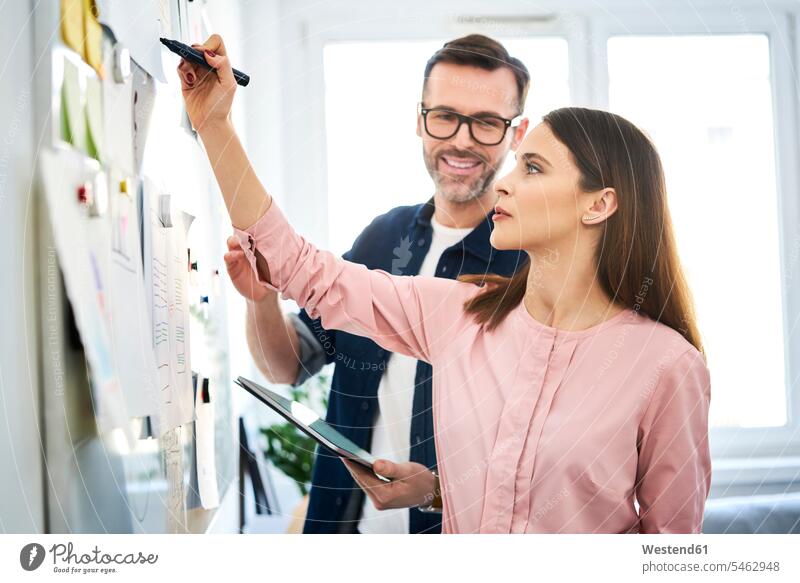 Two colleagues discussing at whiteboard in office white board offices office room office rooms discussion workplace work place place of work Brainstorming