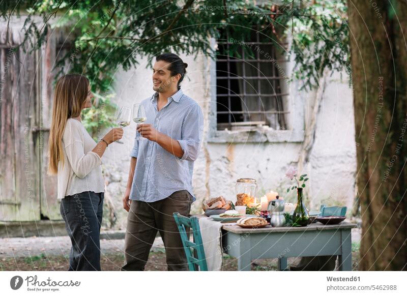 Couple with wine glasses having a romantic candelight meal next to a cottage Wine Glass Wine Glasses Wineglass Wineglasses couple twosomes partnership couples