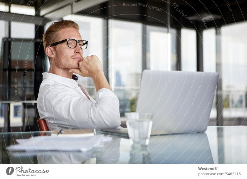 Businessman with laptop on desk in office thinking Laptop Computers laptops notebook Business man Businessmen Business men Office Offices desks computer