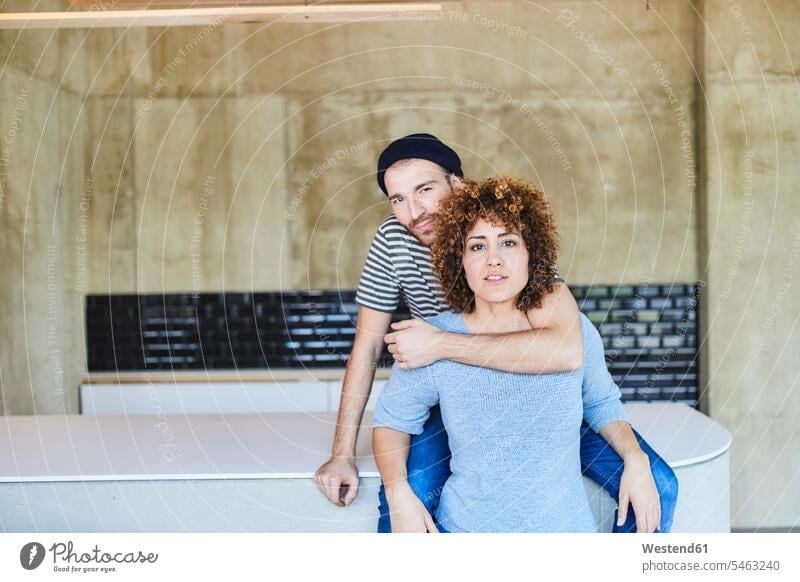 Portrait of a couple hugging Germany young man young men males mid adult women mid adult woman mid-adult women mid-adult woman females casual kitchen counter