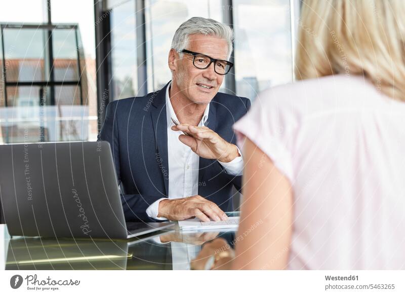 Businessman snd woman sitting in office, discussing project discussion Office Offices projects Seated meeting desk desks Business man Businessmen Business men