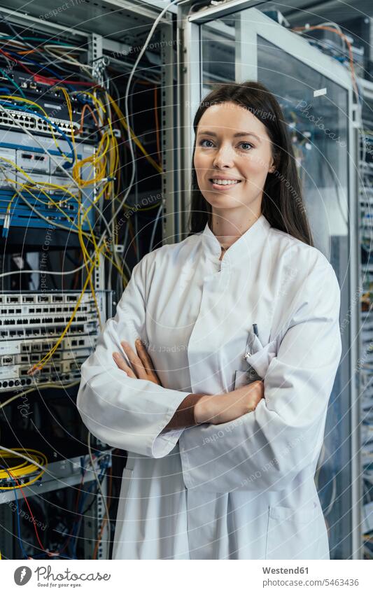 Female IT professional with arms crossed standing in server room color image colour image indoors indoor shot indoor shots interior interior view Interiors