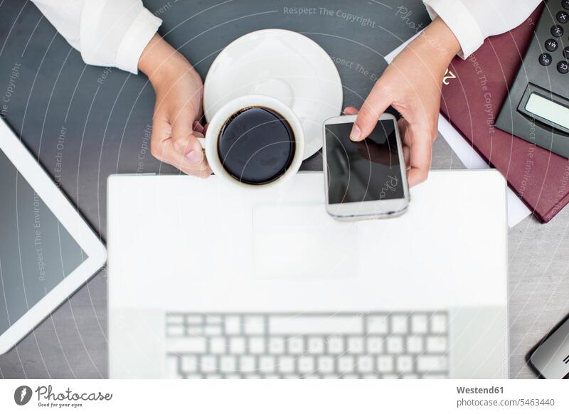 Woman with cup of coffee using smartphone, laptop PA secretaries secretary personal assistants drinking Coffee Cup Coffee Cups Laptop Computers laptops notebook