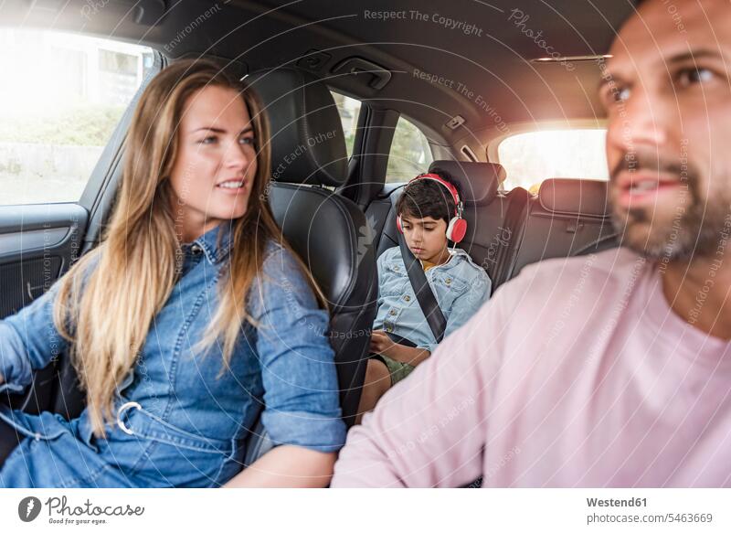 Family on a road trip with boy wearing headphones family families car automobile Auto cars motorcars Automobiles headset driving drive people persons