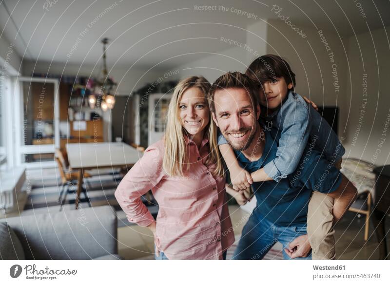 Happy family standing in livingroom, smiling at camera smile delight enjoyment Pleasant pleasure Secure happy Emotions Feeling Feelings Sentiment Sentiments