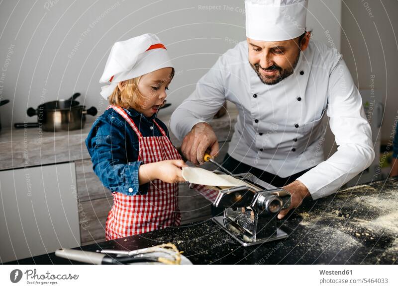 Father and daughter making homemade pasta with pasta machine in kitchen at home Chefs cook cooks hold learn smile delight enjoyment Pleasant pleasure