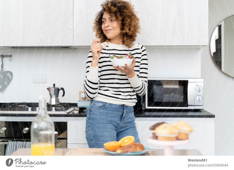 Woman eating strawberries at home Fruit Fruits smiling smile woman females women kitchen domestic kitchen kitchens Breakfast Food foods food and drink Nutrition