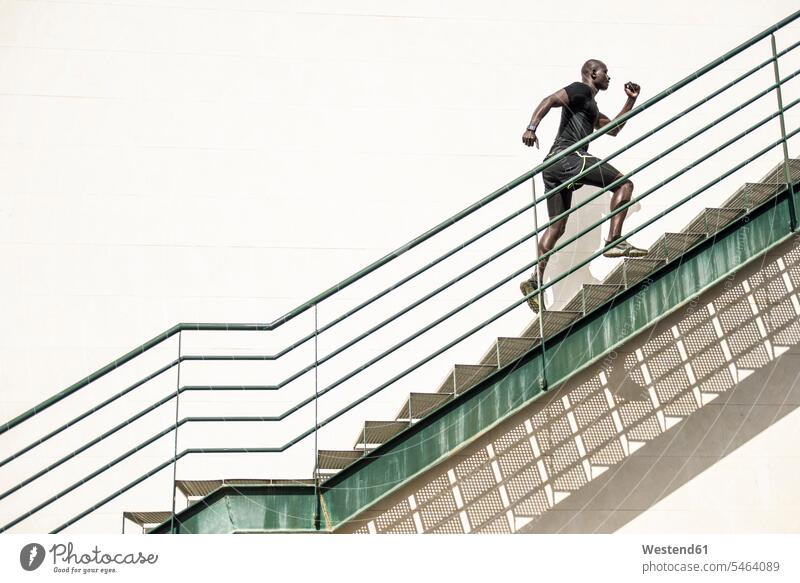 Man in black sportswear running up staircase upwards man men males stairs stairway Sportswear Activewear Sport Clothes Sports Clothes Sports Wear