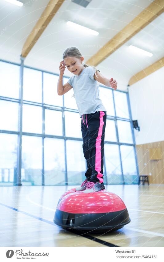 Schoolgirl balancing on exercise equipment in gym class balance schoolgirl female pupils School Girl schoolgirls School Girls schools Exercising Equipment