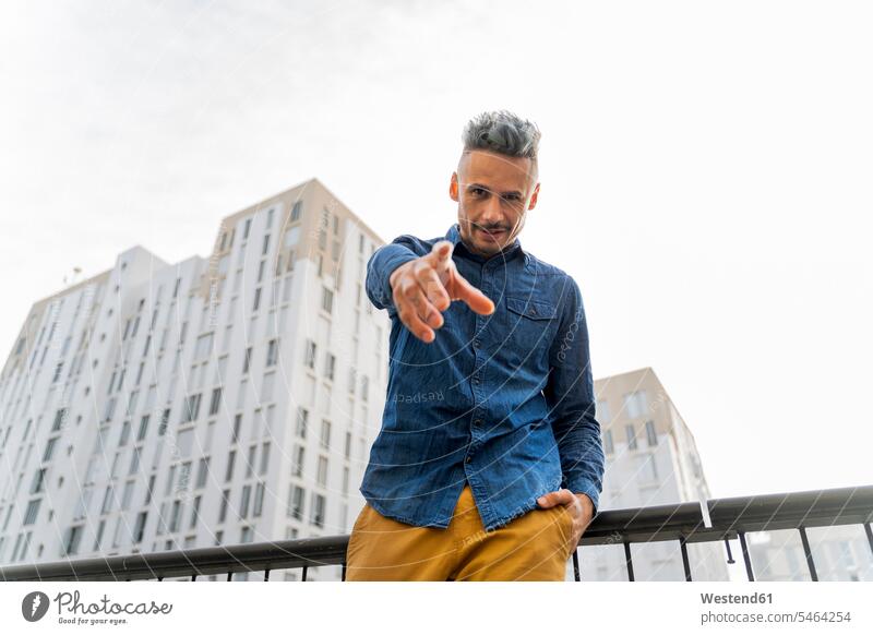 Confident man pointing while standing against sky color image colour image Spain outdoors location shots outdoor shot outdoor shots day daylight shot