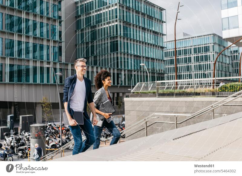 Two colleagues walking outside office building in the city office buildings town cities towns going built structure built structures outdoors outdoor shots