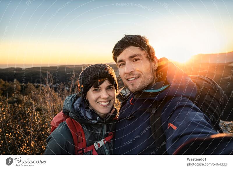 Selfie of happy couple at the Ligurian coast at sunset, Finale Ligure, Italy touristic tourists back-pack back-packs backpacks rucksack rucksacks coat coats