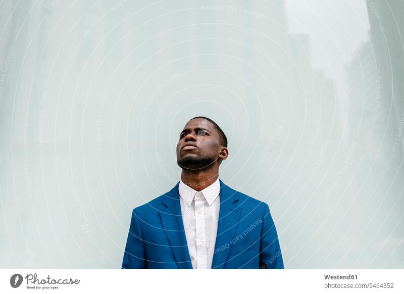 Thoughtful male professional looking away while standing against window in city color image colour image Spain outdoors location shots outdoor shot