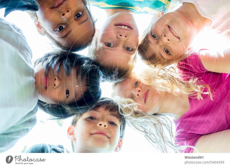 Group of children, sticking heads together, upward view friends smile look seeing viewing delight enjoyment Pleasant pleasure happy Contented Emotion pleased