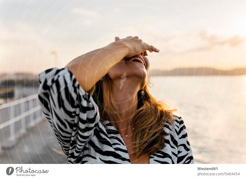 Smiling woman covering face with hand against clear sky color image colour image outdoors location shots outdoor shot outdoor shots sunset sunsets sundown