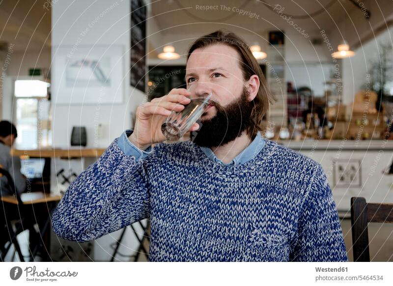 Man with beard sitting in cafe, drinking water man men males portrait portraits full beard Seated amiable likeable Water Adults grown-ups grownups adult people