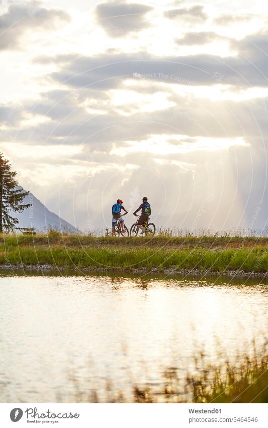 Austria, Tyrol, Mountainbikers in the evening light Taking a Break resting break couple twosomes partnership couples female mountain biker Adventure adventurous