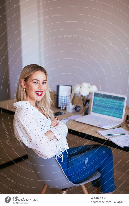 Blond businesswoman sitting at desk, working laughing Laughter businesswomen business woman business women blond blond hair blonde hair At Work office offices