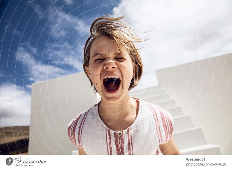 Girl with windswept hair, screaming out loud shout shouting defiance building buildings built structures stairway skies clouds location shot location shots