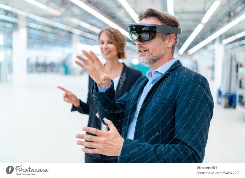 Businessman with AR glasses and businesswoman in a factory hall business life business world business person businesspeople associate associates